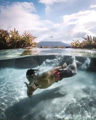 Piscoandbier diving in hot spring of The Springs Resort with view of La Fortuna volcano
