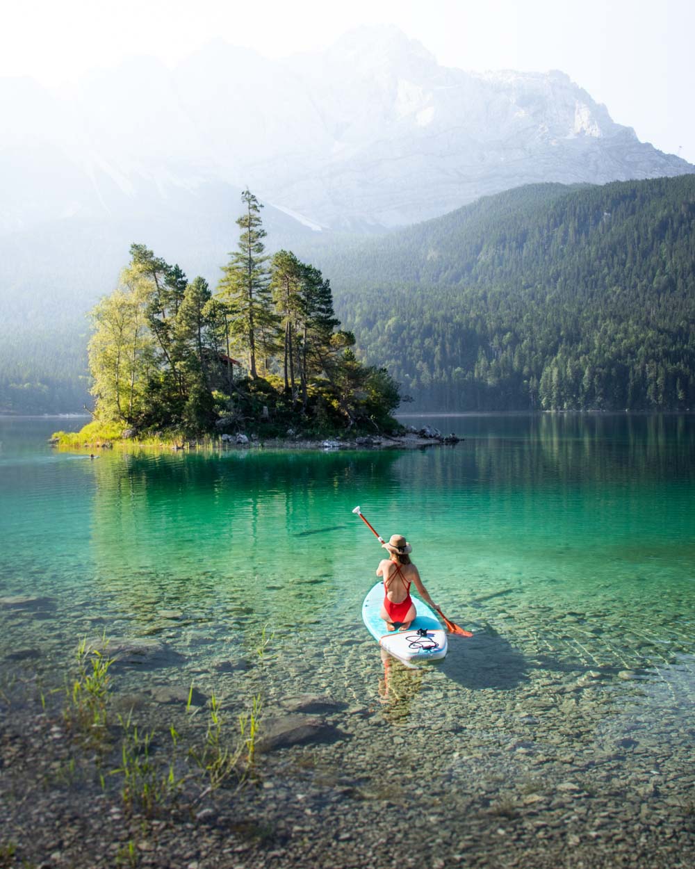 Paddleboarding at crystal clear lake Eibsee with no light reflection in water